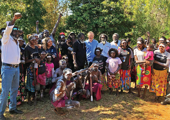 The Governor stands among a semi-circle of members of the Yirrkala community who are looking on or raising their fists in an expression of strength and joy.
