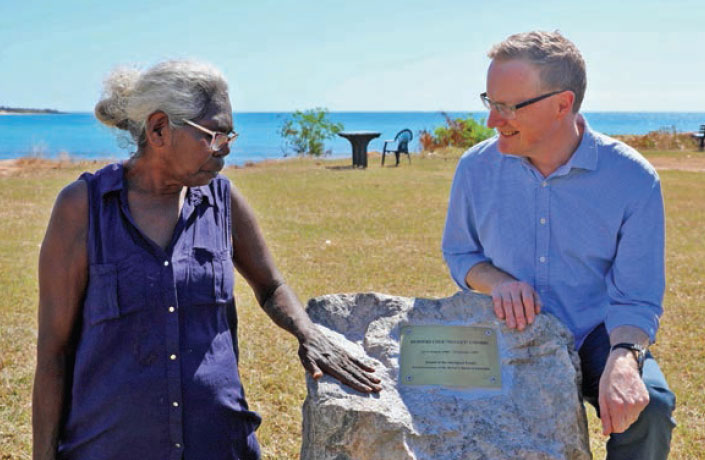 Banduk Marika touches the stone holding the plaque while Governor Philip Lowe watches on.