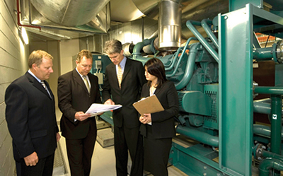 Photograph: Richard Mayes, Head of Financial Management Department, third from left, inspects the auxiliary generator installation at the business resumption site with, from left to right, Martin Patience of Grindley Construction (builder), Rudi Valla of Dem (architect) and Matilde El Azzi from the RBA project team.