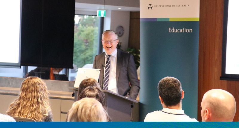 Dr Lowe addressing a group of teachers behind a lectern.