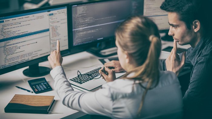 A woman explains the content of a computer screen to a male colleague