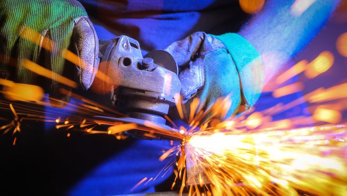 An angle grinder cuts through a steel pipe causing sparks to fly