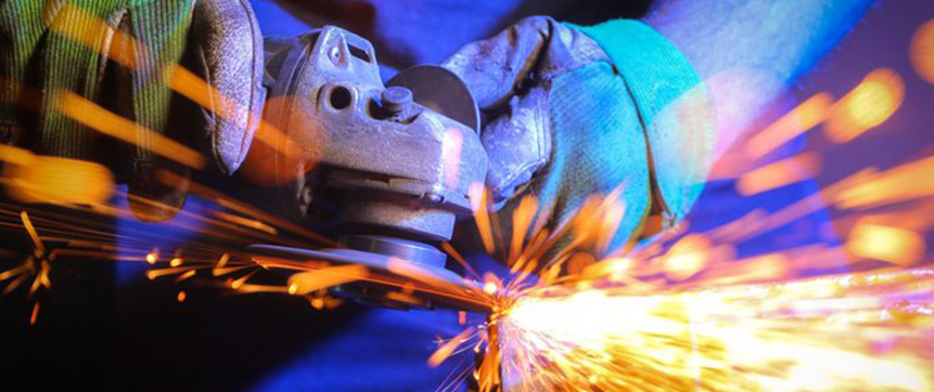 An angle grinder cuts through a steel pipe causing sparks to fly