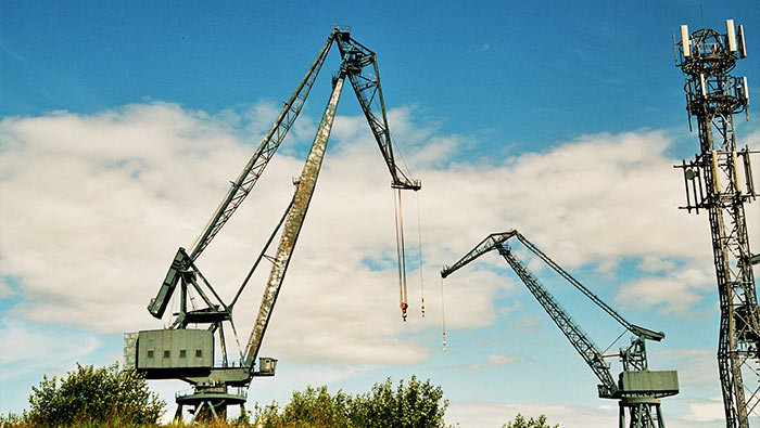 Two construction cranes dominate the sky next to a mobile tower
