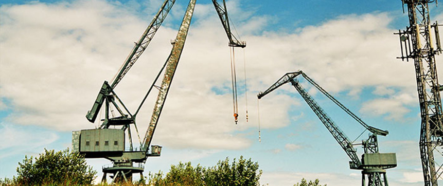 Two construction cranes dominate the sky next to a mobile tower