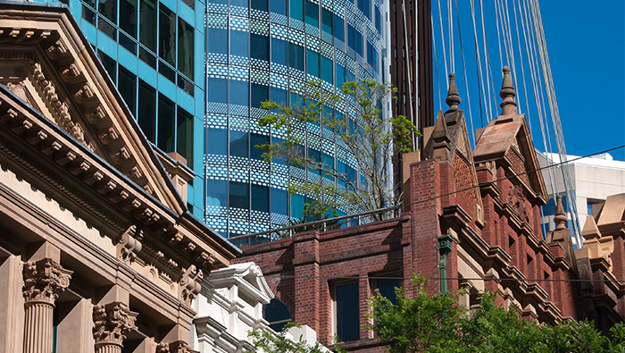 Old sandstone buildings stand out against glass skyscrapbers in the background