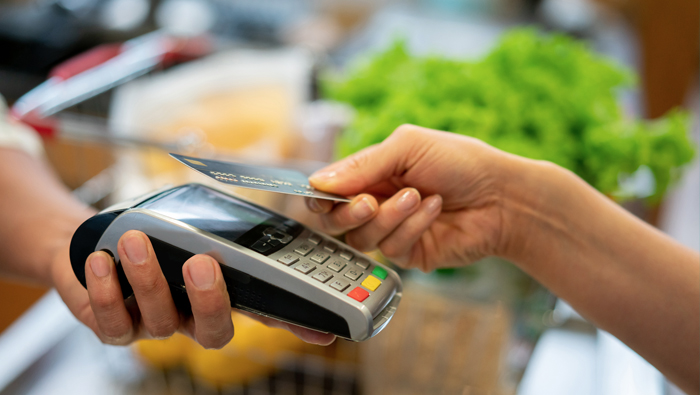A customer holds their credit card above an eftpos reader.