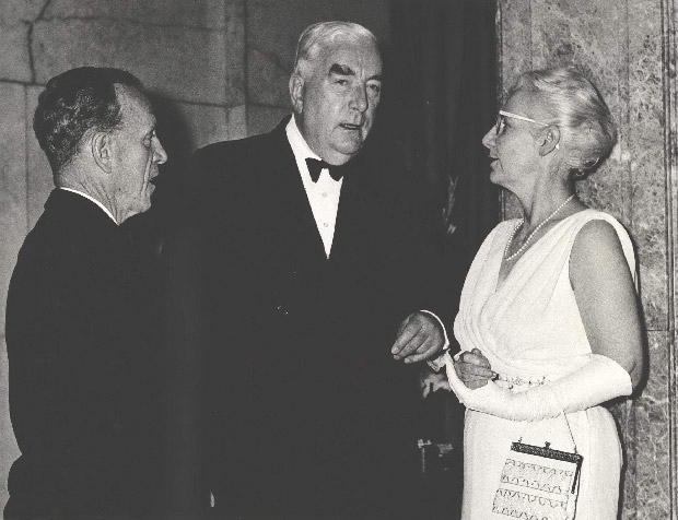 Archival photo of Dr HC Coombs outside the Commonwealth Bank of Australia building (corner of Pitt Street and Martin Place) talking to the Rt Hon. R.G. (Bob) Menzies, Prime Minister, and Mrs Coombs (in gloves and wearing pearls).