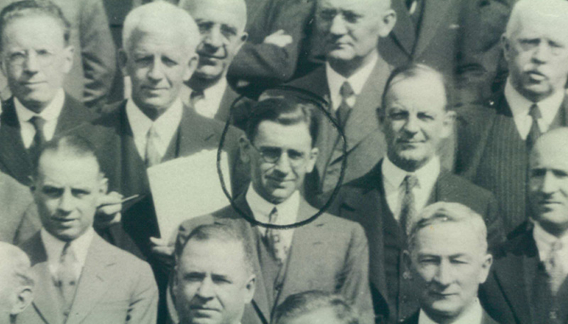 Black and white photo of some of the attendees at the Imperial Conference in 1932. The attendees are in suits, standing and looking direct at the camera. Leslie Melville is standing in the centre and a circle has been drawn around him. He is wearing glasses, a suit and a tie.