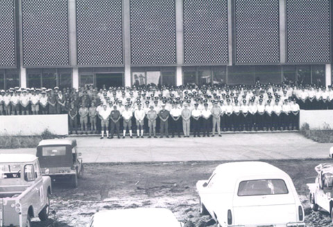 Police contingent and service people for the operation following Cyclone Tracy, outside the Reserve Bank of Australia's Darwin branch, 1974.<br><br> The Darwin branch building survived the cyclone with little damage, and served as the emergency coordination and communications centre.<br><br> <small>RBA Archives PN-009358</small>